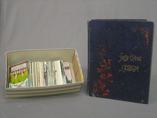 A shoe box containing a collection of various postcards together with a blue card postcard album