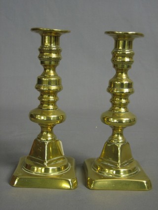 A pair of 19th Century brass candlesticks with ejectors raised on square bases 8"