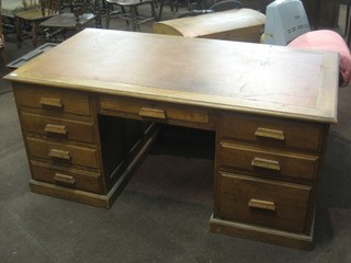 A large honey oak kneehole pedestal desk with inset writing surface, fitted 1 long drawer and 8 short drawers 66" (in one section)