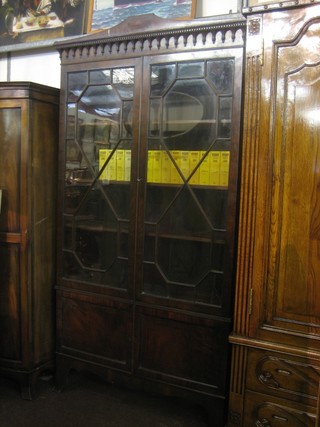 A Georgian mahogany bookcase on cabinet, the upper section with moulded cornice, fitted shelves enclosed by astragal glazed panelled doors, the base fitted a cupboard enclosed by panelled doors, raised on bracket feet 41"