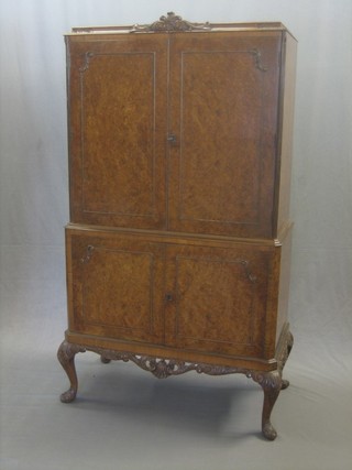 A Queen Anne style walnut cocktail cabinet, the upper section enclosed by panelled doors, the base fitted a cupboard enclosed by panelled doors, raised on cabriole supports 33"