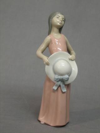 A Lladro figure of a standing girl with hat, base marked 5008 9"