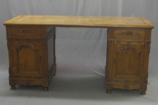 A carved oak kneehole pedestal desk fitted a drawer above a cupboard enclosed by panelled doors, raised on turned supports 62"