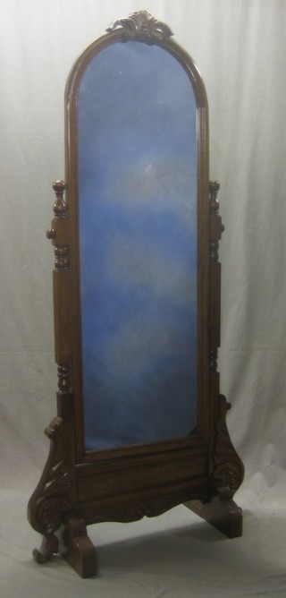 An arched plate cheval mirror contained in a mahogany swing frame