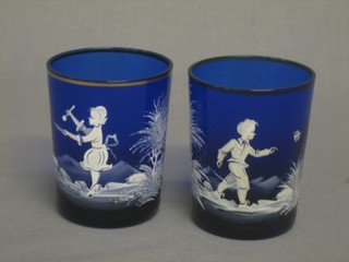 A pair of Mary Gregory style blue glass beakers with enamelled boy and girl decoration