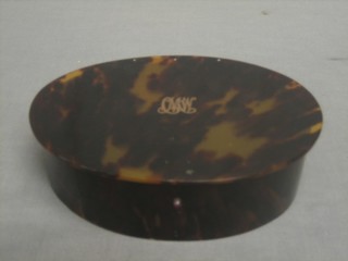 An oval tortoiseshell dressing table box with hinged lid, inlaid gold monogramme to the top and with silver hinges Birmingham 1915 (slight tear to back) 8"
