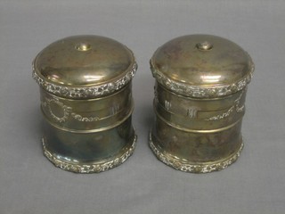 A pair of Edwardian cylindrical silver plated jars and covers with cast decoration 4"