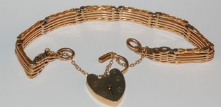 A gold gate bracelet with heart shaped padlock