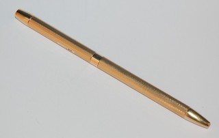 A 9ct gold cased propelling pen contained in a 9ct gold engine turned case