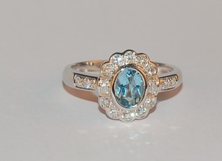 A lady's 18ct white gold dress ring set an oval cut aquamarine supported by diamonds, approx 0.73/0.45ct