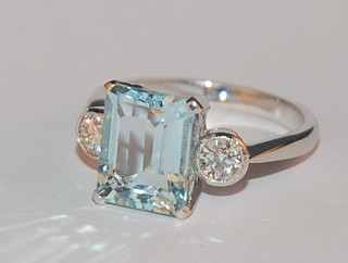 A lady's 18ct gold dress ring set a rectangular cut aquamarine supported by 2 diamonds, approx 0.40/3.20ct