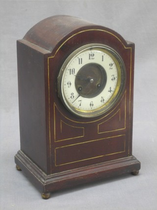 An Edwardian striking mantel clock with porcelain dial and Roman numerals contained in an arch shaped mahogany case