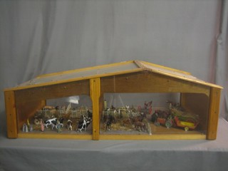 An excellent display of Britains farmyard figures, animals, tractors, hoes etc, contained in a purpose built wooden barn display cabinet