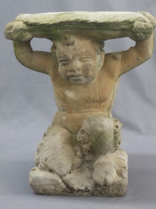 A well weathered garden seat in the form of a cherub supporting a cushion 18"