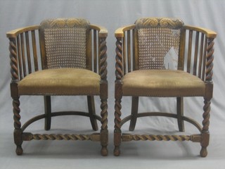 A pair of 1930's carved oak tub back chairs with woven cane panels, raised on spiral turned supports