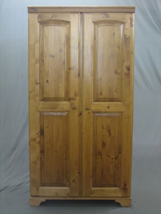 A pine wardrobe by Ailesbury pine, enclosed by arch shaped panelled doors, raised on bracket feet 38"