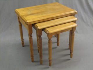 A nest of 3 pine interfitting coffee tables, raised on turned supports 24"