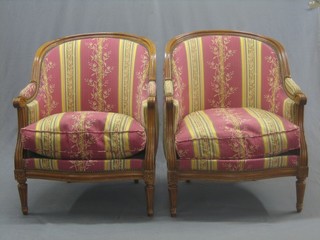 A pair of Continental mahogany show frame tub back chairs upholstered in striped material and raised on turned and fluted supports