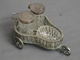 An Edwardian cut glass silver plated condiment set contained within a circular silver plated basket, raised on 3 wheels