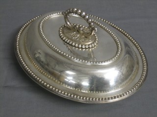 An oval silver plated entree dish and cover with bead work border