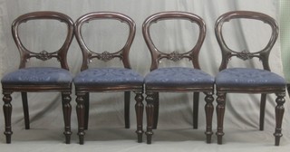 A set of 4 Victorian style mahogany balloon back dining chairs with carved mid rails, raised on turned and reeded supports