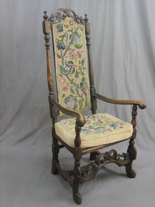 An 18th Century walnut open arm carver chair with Berlin wool work back and seat, raised on turned and block supports (some old worm and restoration)