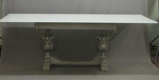 A silver painted "Designer" refectory style drawleaf dining table with white glass top, raised on carved bulbous supports with H framed stretcher 83"
