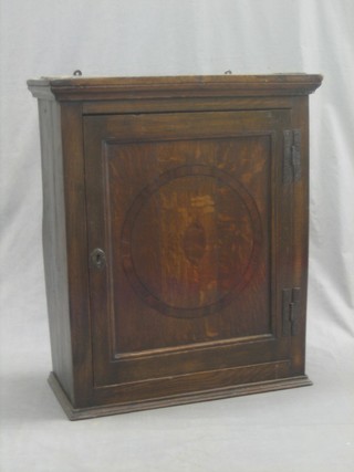 An 18th/19th Century oak hanging cabinet with moulded cornice, fitted shelves enclosed by a panelled door 23"