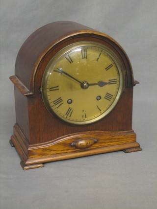 A chiming mantel clock with gilt dial and Roman numerals contained in an arch shaped oak case