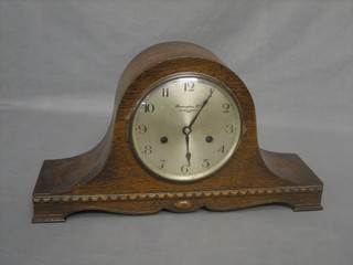 A striking mantel clock with silvered dial and Arabic numerals contained in an oak Admiral's hat shaped case by Bravingtons