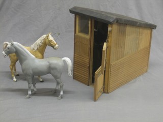 A childs wooden model stable and 3 plastic horses