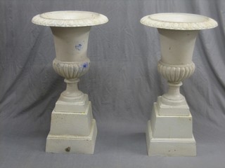 A pair of Victorian style white painted cast iron urns of trumpet form with egg and dart borders, raised on square bases 18"