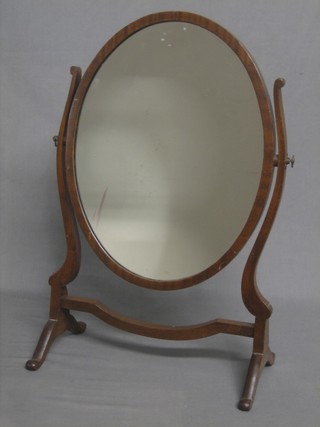 An oval plate dressing table mirror contained in a mahogany swing frame