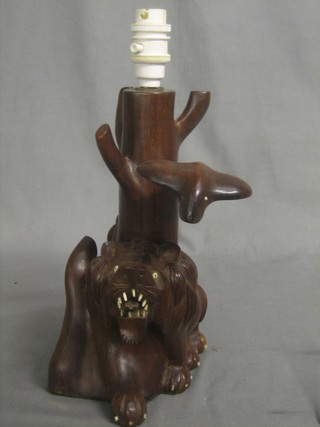 An Eastern carved hardwood table lamp in the form of a lion and cobra 11"