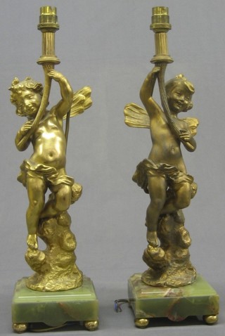 A pair of 19th/20th Century gilt painted spelter table lamps in the form of cherubs, raised on onyx bases with bun feet 18"