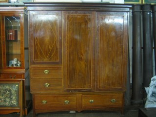 An Edwardian Art Nouveau inlaid mahogany double wardrobe with moulded cornice, having a double cupboard enclosed by panelled doors, the cupboard to side above 2 short drawers, the base fitted 2 long drawers 71"