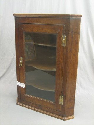An 18th Century oak hanging corner cabinet, the interior fitted shelves enclosed by a glazed panelled door 29"