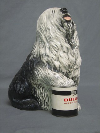 A Beswick figure of a seated  Old English Sheep Dog, right paw on a tin of Dulux paint, the base with gold Beswick mark 12" 