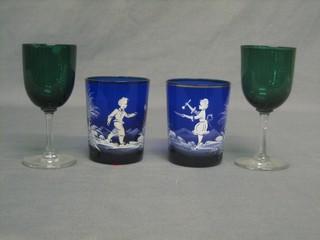 A pair of Mary Gregory style blue glass beakers with enamelled boy and girl decoration and a pair of 19th Century green glass wine glasses with clear glass stems