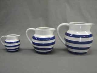 A set of 3 Cornish style graduated blue and white striped pottery milk jugs