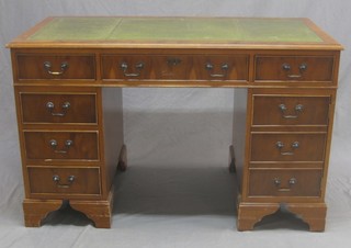 A yew kneehole pedestal desk with inset green leather writing surface above 1 long and 8 short drawers raised on bracket feet 48"