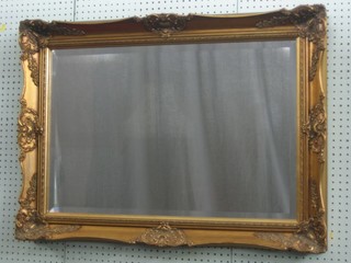 A rectangular bevelled plate wall mirror contained in a decorative gilt frame 37"