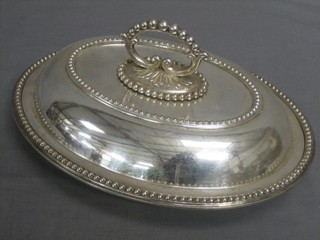 An oval silver plated entree dish and cover with bead work border