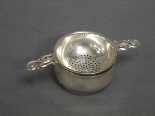 A silver twin handled tea strainer and stand, Birmingham 1960