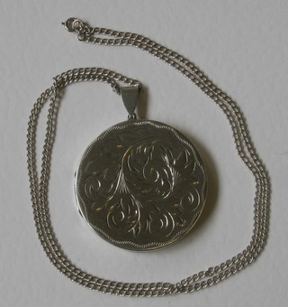 A circular engraved silver locket hung on a silver chain