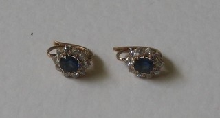 A pair of lady's gold earrings set sapphires surrounded by diamonds