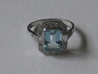 A lady's 18ct white gold dress ring set a rectangular cut aquamarine supported by numerous diamonds, approx 0.50/2.10ct