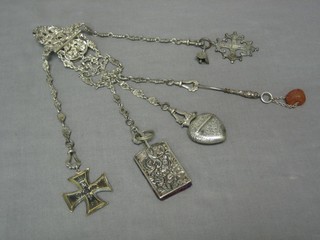 A Victorian 5 string silver chatelaine decorated classical scenes, London 1854, hung an 1870 Iron Cross 2nd Class, a rectangular embossed "silver" pin case, a Continental silver heart shaped locket, an amber coloured stone, a silver plated Continental cross and a Continental silver plated square bell