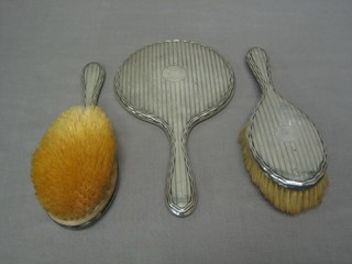 A silver backed 3 piece dressing table set with hand mirror, pair of hair brushes, Birmingham 1920