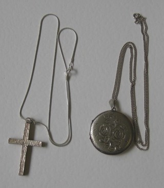 A silver cross hung on a fine chain together with a silver locket